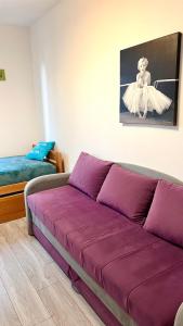 a purple couch in a room with a bed at Pokoje U Hanki in Dziwnów