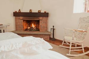 a bedroom with a fireplace and a bed and a chair at La perla nella foresta in Vara Superiore