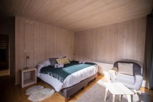 1 dormitorio con 1 cama y 1 silla en Refugio Austral Coigües en Corralco, en Curacautín