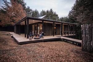 a group of people sitting on the porch of a house at Refugio Austral Coigües en Corralco in Malalcahuello