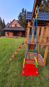 a wooden swing set in a yard with a house at Drevenica Lesanka in Demanovska Dolina