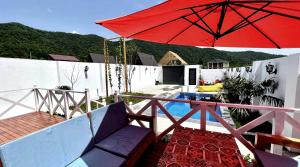 a patio with a red umbrella and a pool at Qafqaz Resort Melisa in Gabala