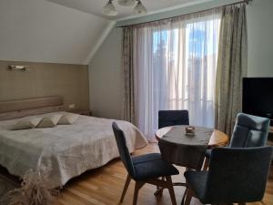 1 dormitorio con 1 cama, mesa y sillas en Birutes Apartments, en Palanga