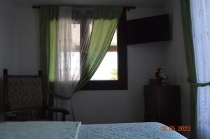 a bedroom with a bed and a window with green curtains at Preciosa casa con aparcamiento a 1km de la Toja in O Grove