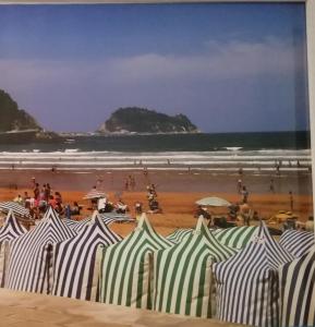 een schilderij van een strand met een stel parasols bij Amplio y soleado Alquilo apartamento entero de 3 hab 5 pax in Zarautz
