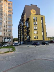 a yellow building with cars parked in a parking lot at Truskavets Oasis Apartments in Truskavets