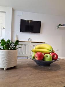 uma taça de fruta sobre uma mesa ao lado de uma planta em Dove Apartments em Oxford