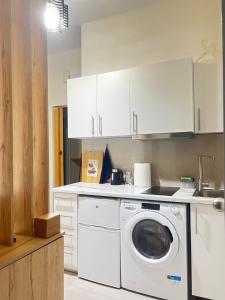 cocina con lavadora y armarios blancos en 一线海景房seaview apartment, en Artemida
