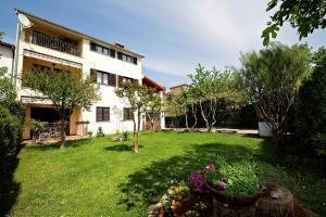 ein Haus mit einem Garten mit Blumen und Bäumen in der Unterkunft Apartments Perkovic in Fažana