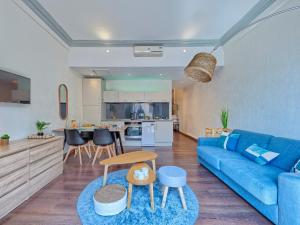Appartement Cosy : Proche Mer et Gare في خوان ليس بينس: غرفة معيشة مع أريكة زرقاء ومطبخ