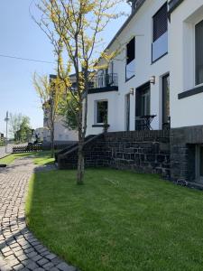 Biały dom z drzewem w ogrodzie w obiekcie Ferienhaus Stadtblick w mieście Bad Marienberg