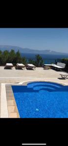 a blue swimming pool with benches and the ocean in the background at Luxury Villa with amazing view, Cesme in Cesme