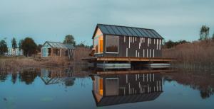 a house sitting on top of a body of water at Million star hotel Latgale in Nastrova