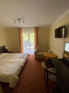 a hotel room with a bed and a couch and a television at OW Posejdon in Łazy
