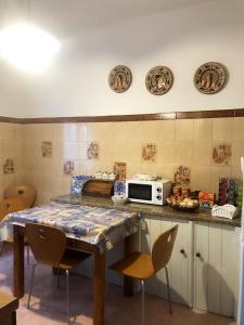eine Küche mit einem Tisch mit Stühlen und einer Mikrowelle in der Unterkunft A casa di Maria in Ozieri