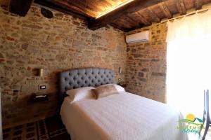 una camera con un letto in un muro di mattoni di Maremma Holidays- La Casa Di Rocca a Scarlino