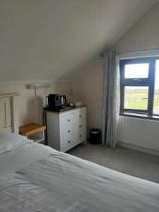 a bedroom with a white bed and a window at Lios Éinne House Accommodation in Inisheer