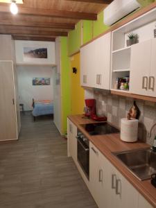 una cocina con armarios blancos y paredes verdes en GS APARTMENT, en Gythio