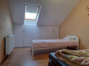 um quarto no sótão com 2 camas e uma janela em Apartman Avram em Kotor-Varoš
