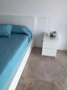a bedroom with a bed and a nightstand with a blue bed at Thalassa Court Sandy Beach Apartment in Protaras