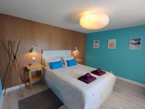 a bedroom with a large white bed with blue walls at Sunset House in São Julião