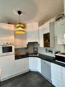 uma cozinha com armários brancos e um candeeiro em Bel appartement /30 min de Paris em Louveciennes