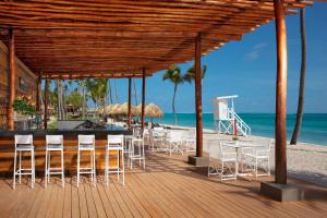 ein Restaurant am Strand mit Stühlen und Tischen in der Unterkunft Dreams Flora Resort & Spa - All Inclusive in Punta Cana