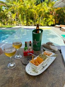a table with a plate of food and glasses of wine at Lá em Casa - Guest House in Barra Grande