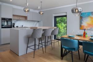 a kitchen with white cabinets and blue bar stools at Villa Voyage in Zadar
