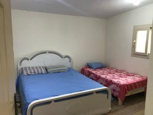 een slaapkamer met een blauw bed en een rood matras bij Ageba Beach Marsa Matrouh Chalet 103 صف اول بحر in Zâwyet Umm el Rakham