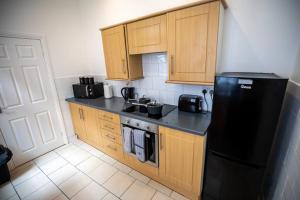 una cucina con armadi in legno e frigorifero nero di Blessed Burnville Home with Parking a Sunderland