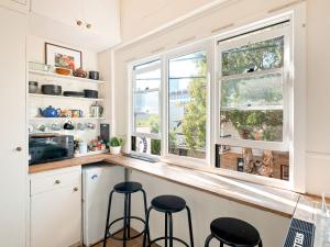 a kitchen with two windows and a counter with stools at Lord Wolseley Hotel in Sydney