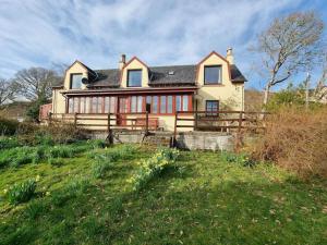 a large house sitting on top of a lush green field at Altdarroch Farm House in Kinlocheil