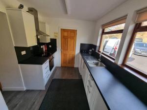 a kitchen with white cabinets and a sink and a window at Altdarroch Farm House in Kinlocheil +8 photos