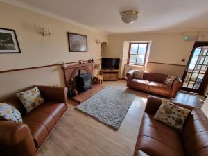 a living room with leather furniture and a fireplace at Altdarroch Farm House in Kinlocheil