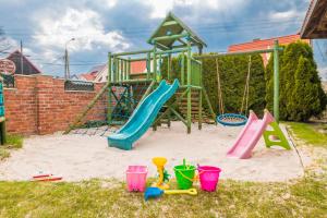 a playground with a slide and buckets in the sand at Villa Akacja in Łeba