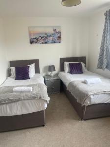 um quarto com 2 camas e almofadas roxas em Steeple House em Higham Ferrers