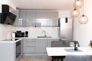 eine Küche mit weißen Schränken und einem Tisch mit Stühlen in der Unterkunft Bepa in Supetar