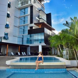 a woman sitting in a swimming pool in front of a building at RBB BRITO HOTEL in Tarapoto