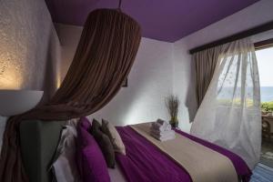 una camera da letto con un letto con pareti viola e una finestra di Villa Georgia Apartments & Suites a Kalamaki