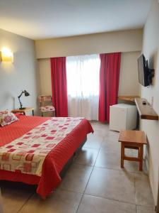 1 dormitorio con cama roja y cortinas rojas en Hostal El Korú en San Carlos de Bariloche