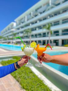 two people holding cocktails in front of a swimming pool at Xeliter Cana Rock Punta Cana in Punta Cana