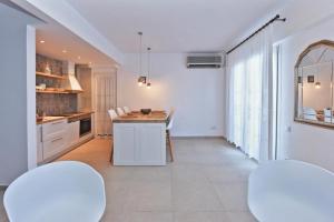 a kitchen with white cabinets and a table and chairs at Afitos Sofia’s village in Afitos