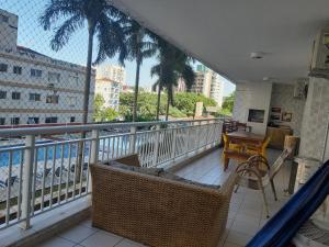 een balkon met een tafel en stoelen en palmbomen bij GUARUJÁ ASTURIAS, LAZER COMPLETO, AR CONDICIONADO E VARANDA GOURMET in Guarujá