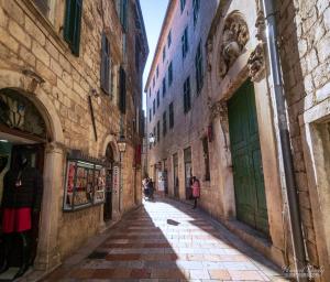 an alley in an old town with people walking down it at Cozy 2 Bedroom Apartment in Antique Bizanti Palace in Kotor