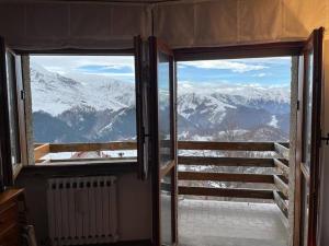 una puerta abierta con vistas a las montañas cubiertas de nieve en Monolocale Bellavista en Prato Nevoso