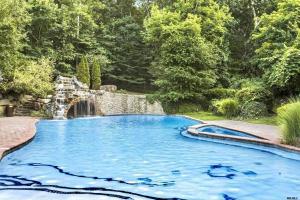 a swimming pool with a waterfall in a garden at Amazing Pool Private Oasis! 25 Mins 2 Westhampton! in Wading River