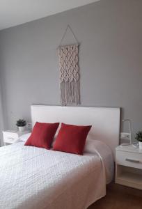 1 dormitorio con cama blanca y almohadas rojas en Apartamento Serena beach, en Águilas