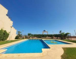 a large swimming pool with blue water in a yard at Piso Serena beach in Águilas