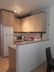 cocina con armarios de madera y nevera blanca en Apartamento Serena beach, en Águilas